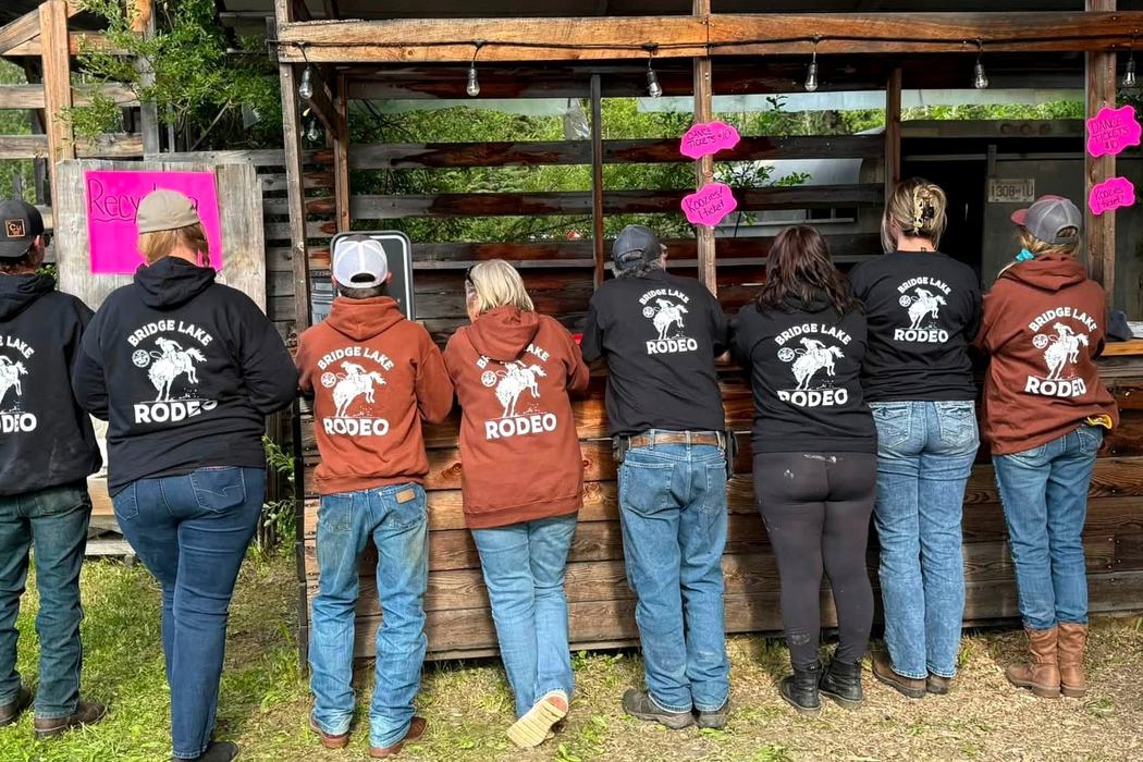 Rodeo crew lined up at the concession window in Bridge Lake Rodeo hoodies.