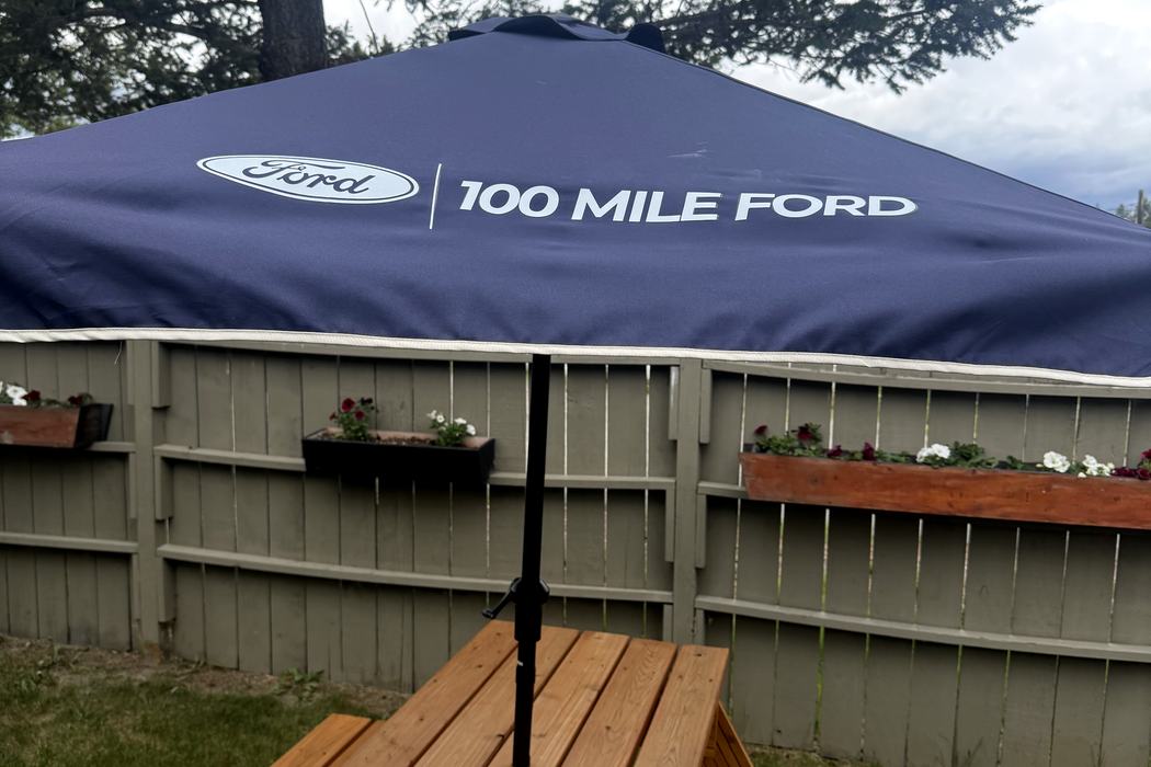 Branded umbrella opened over a picnic table.