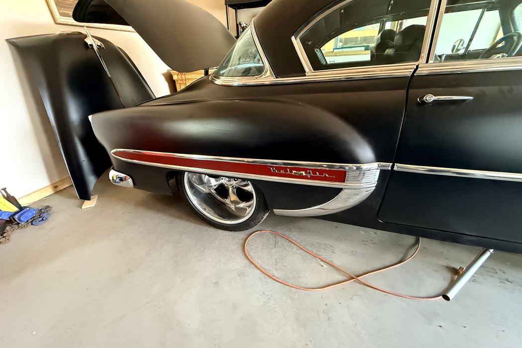 1954 Chevrolet Bel Air quarter panel with red vinyl spear insert behind chrome trim.