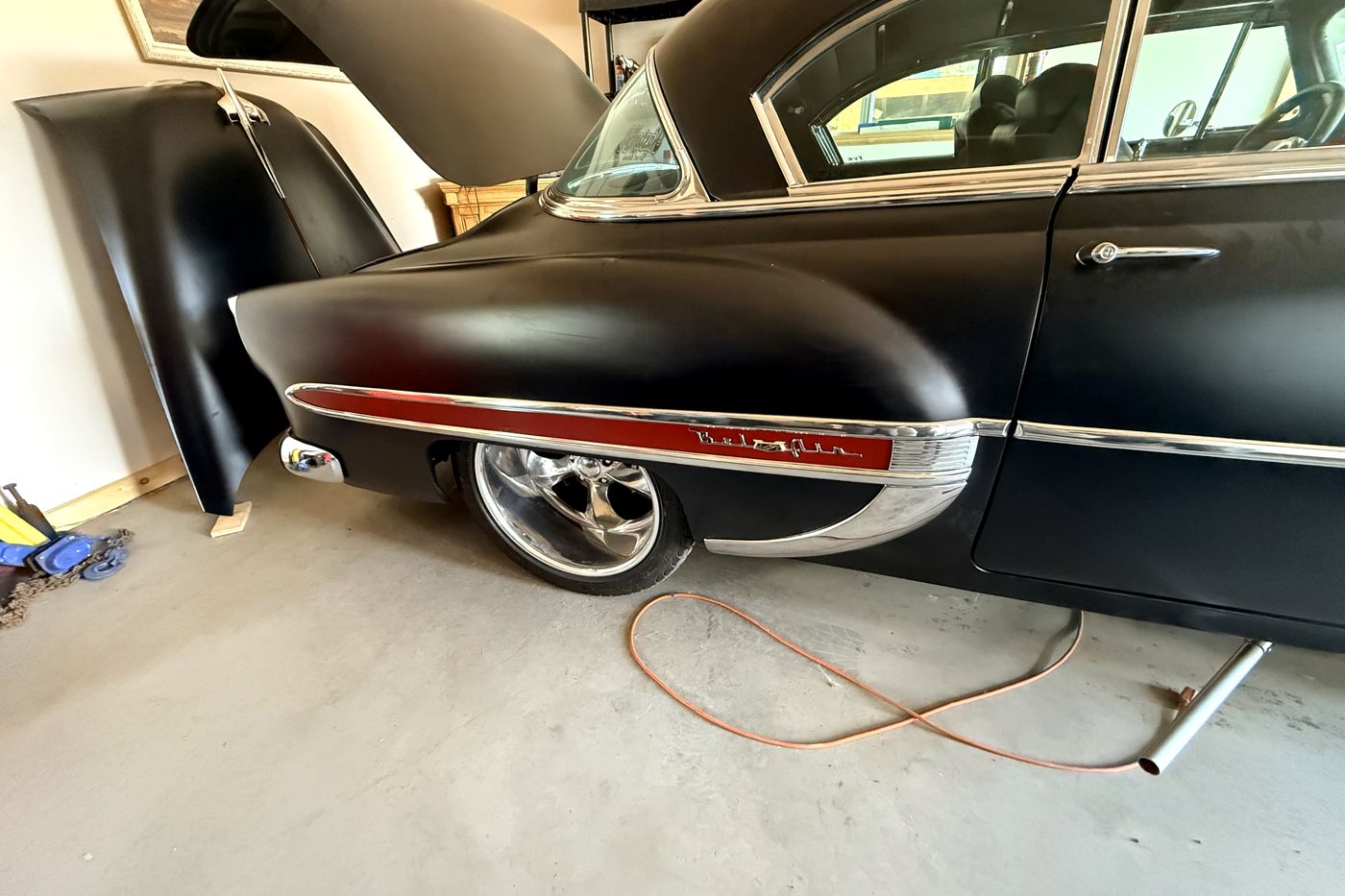 1954 Chevrolet Bel Air quarter panel with a red vinyl spear insert behind chrome trim.