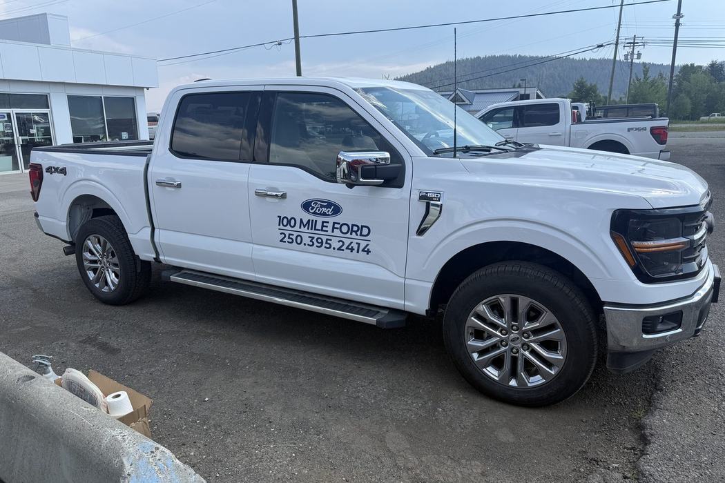 White Ford F-150 with 100 Mile Ford door decals on the dealership lot.